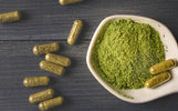 Een stenen Boeddha presenteert een schaal met groen kratom poeder in een tropische setting bij Novus Fumus.