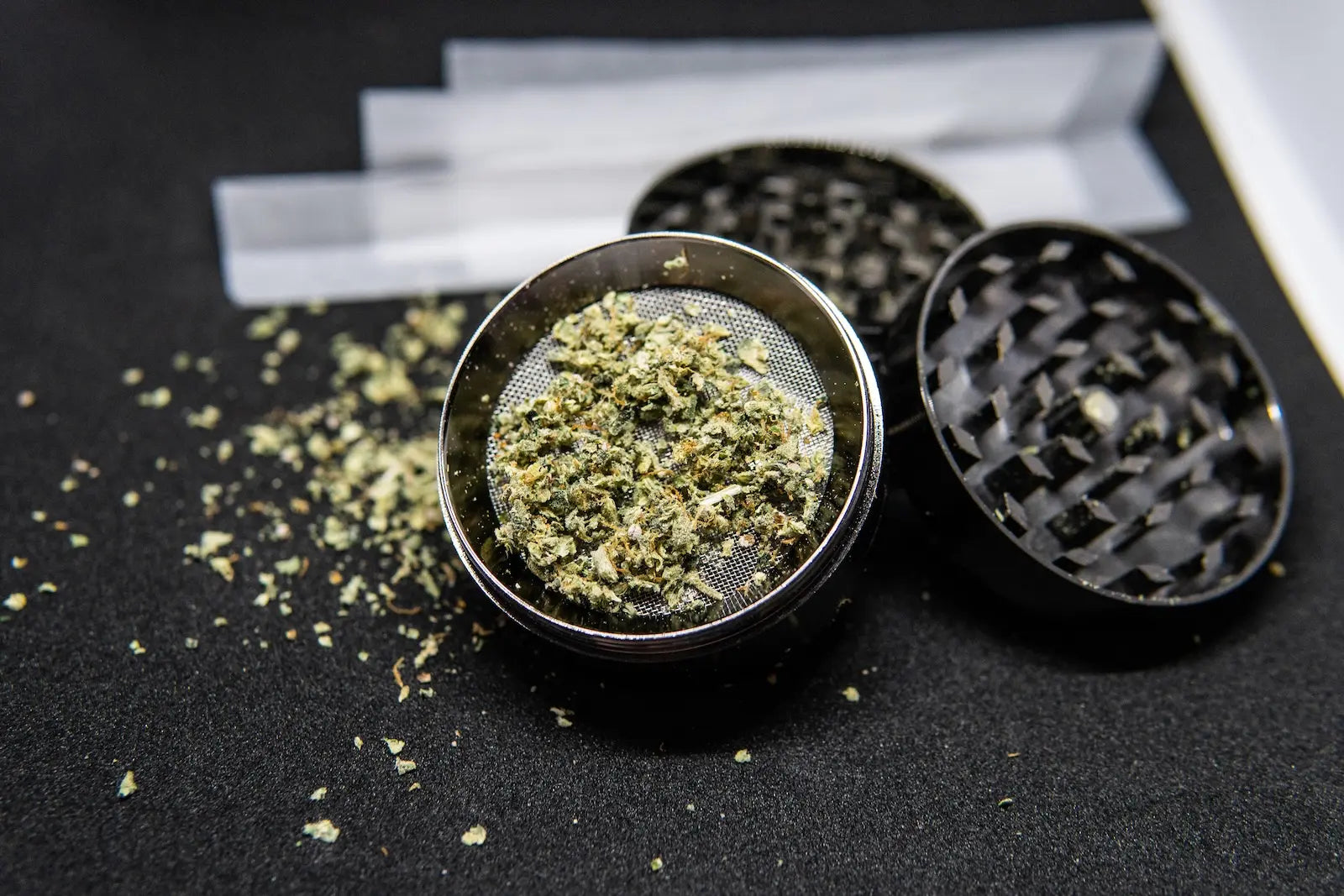 Metalen cannabis grinder met gemalen wiet en vloeitjes