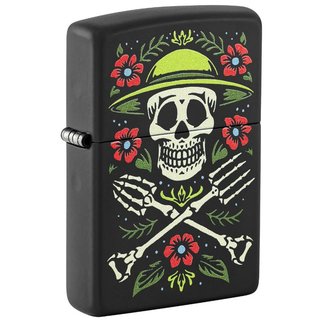 Front view of a Black Matte Zippo lighter featuring a colorful design of a skeleton gardener wearing a green hat, with crossed garden forks and surrounded by red flowers